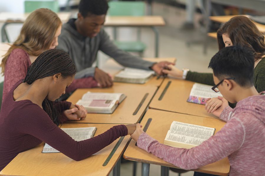 children praying at school desk