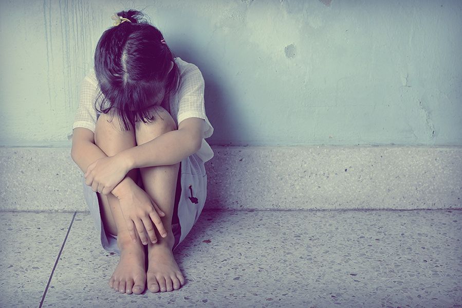 little girl leaning against wall and crying