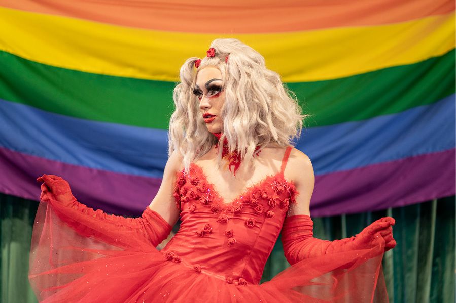 drag queen performing in front of pride flag