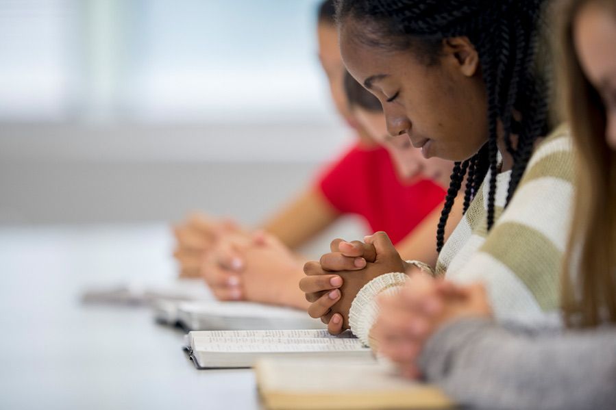 girl praying over bible in classroom