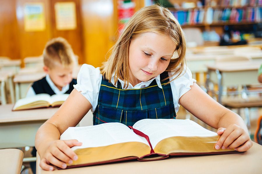 girl reading bible in school classroom