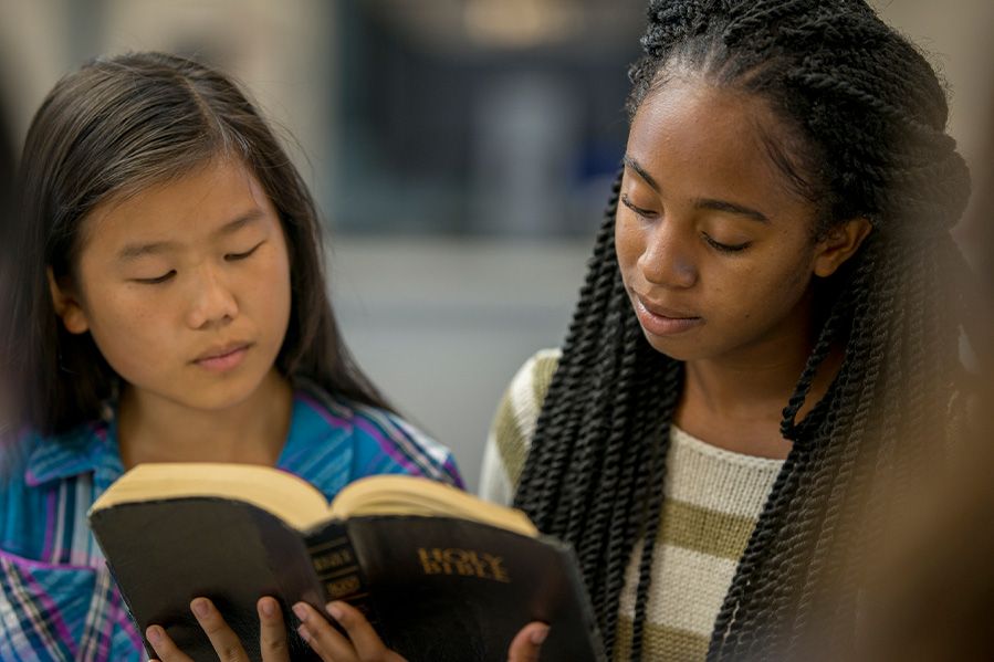 two high school girls reading the holy bible