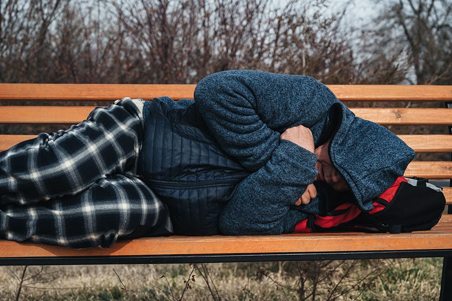 homeless man sleeping on park bench