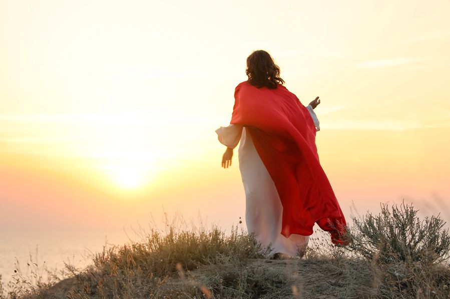 jesus christ standing on hill overlooking sunrise