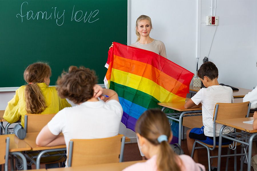 teacher holding lgbtq flag in public school classroom