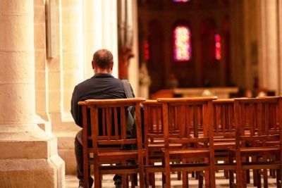 man sitting alone in church pews