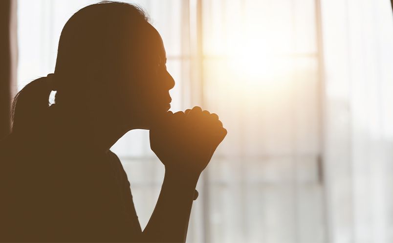 silhouette of woman praying at home