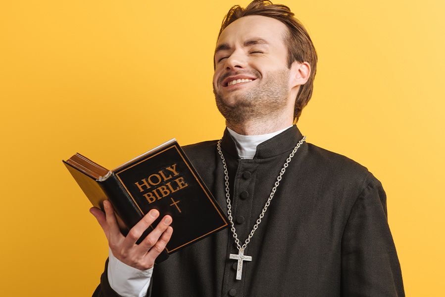 Catholic priest laughing while reading the Bible