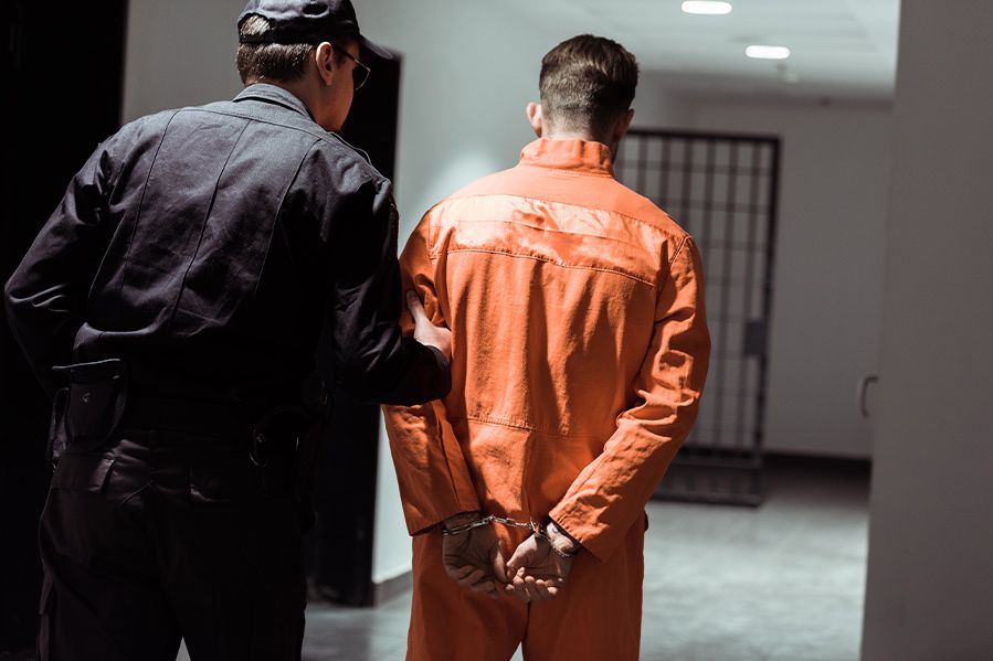 handcuffed prisoner being escorted in prison by guard