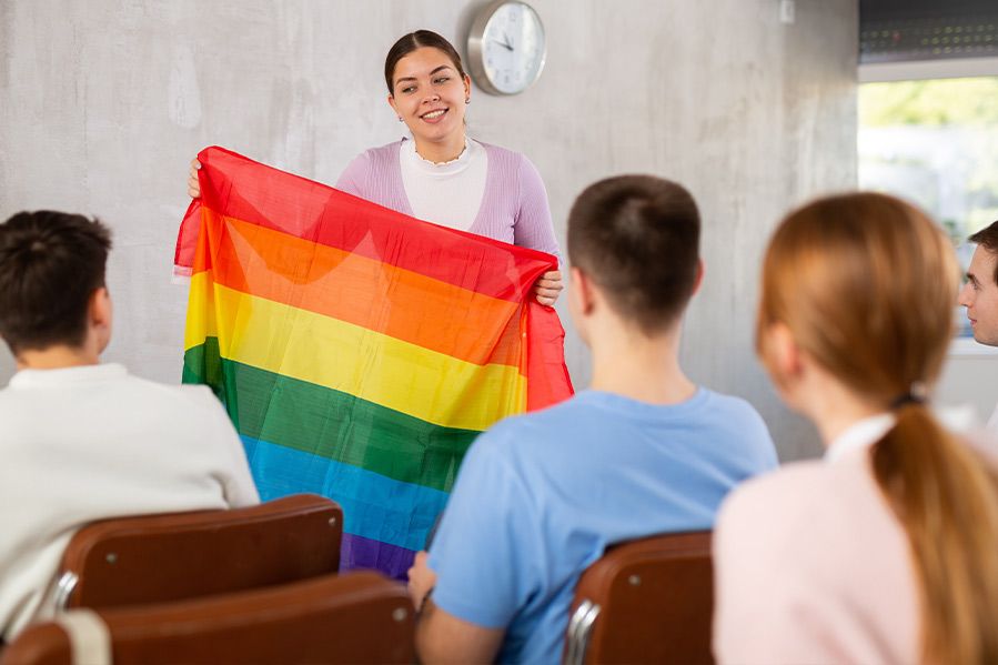 female teacher holding lgbt pride flag in classroom