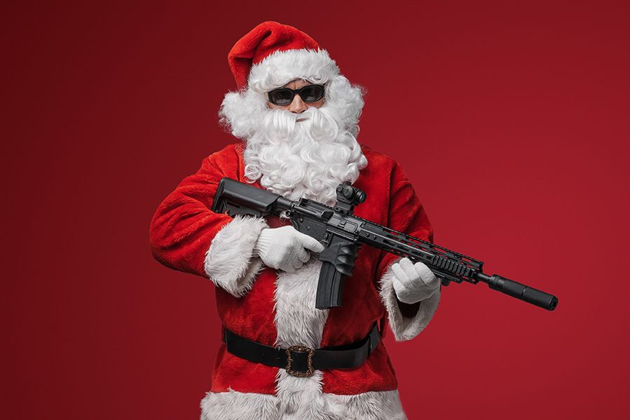 Santa Claus holding machine gun on red background