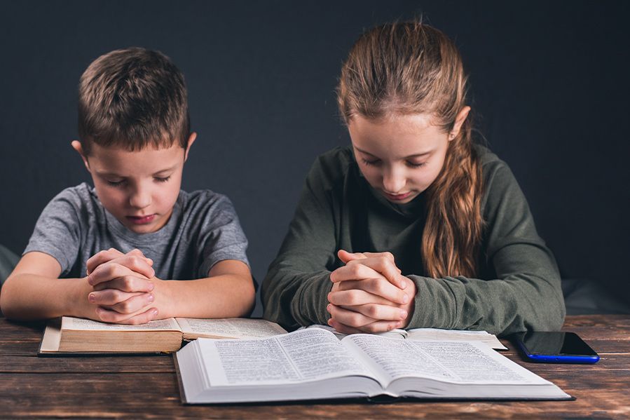 children praying and reading bible in classroom