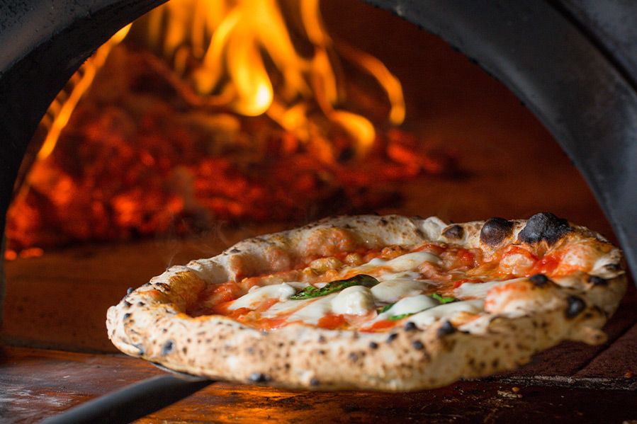 pizza coming out of woodfire oven