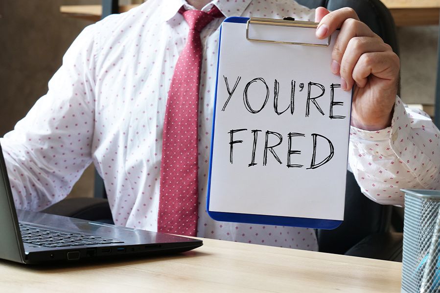 office worker holding sign that says you're fired