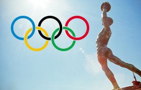 statue of ancient olympian with modern olympic rings