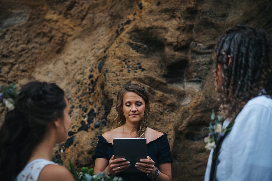 An officiant conducting a vow renewal ceremony with a rock backdrop