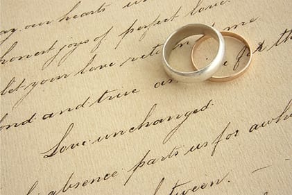 A wedding ring set on top of written vows